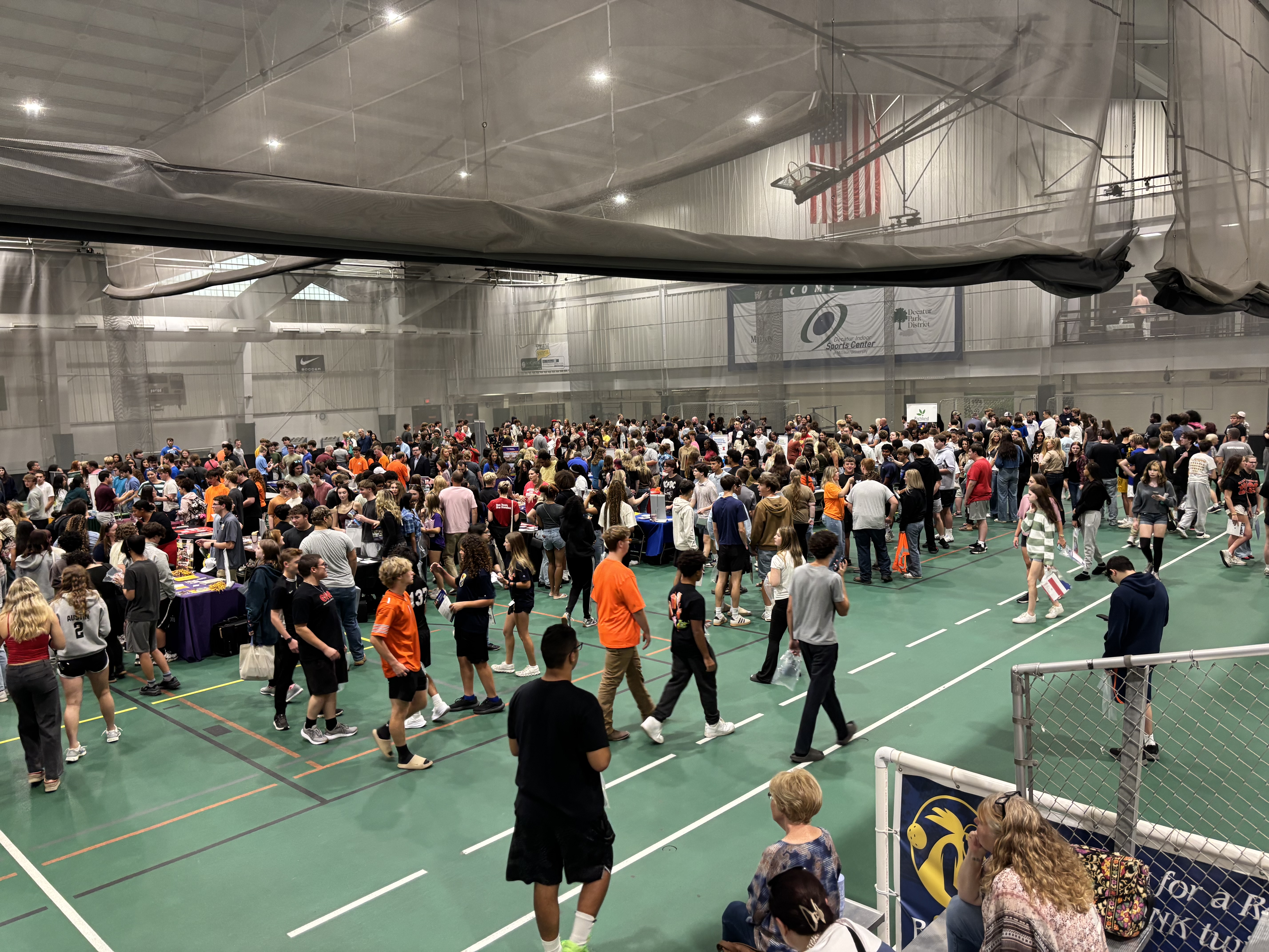 Numerous students walk around a gym collecting information from tables at the Macon County College & Career Fair