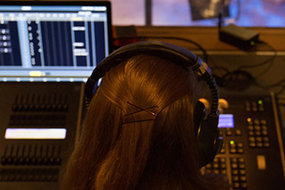 student with headphones facing an audioboard