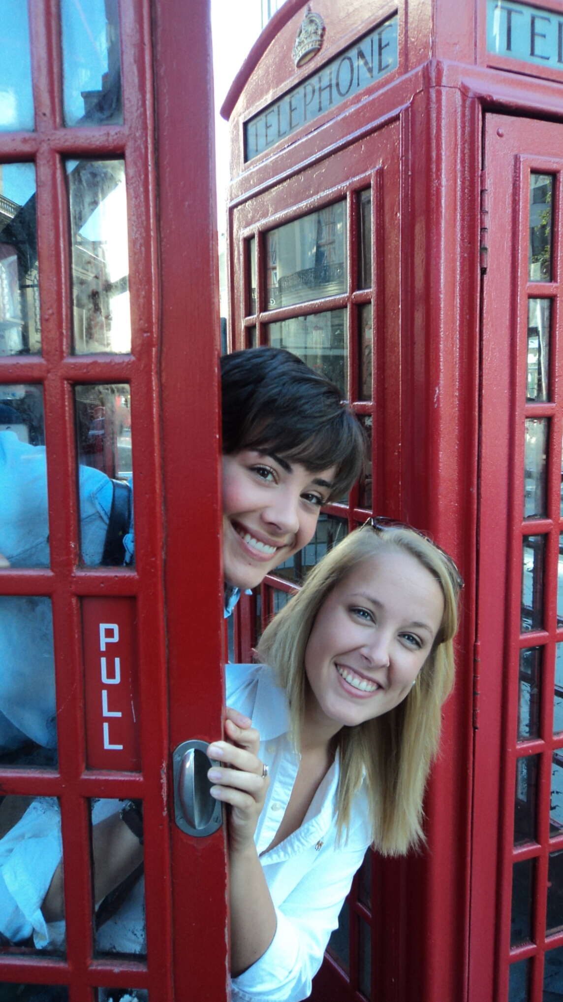 Two students peeking out of a phone booth