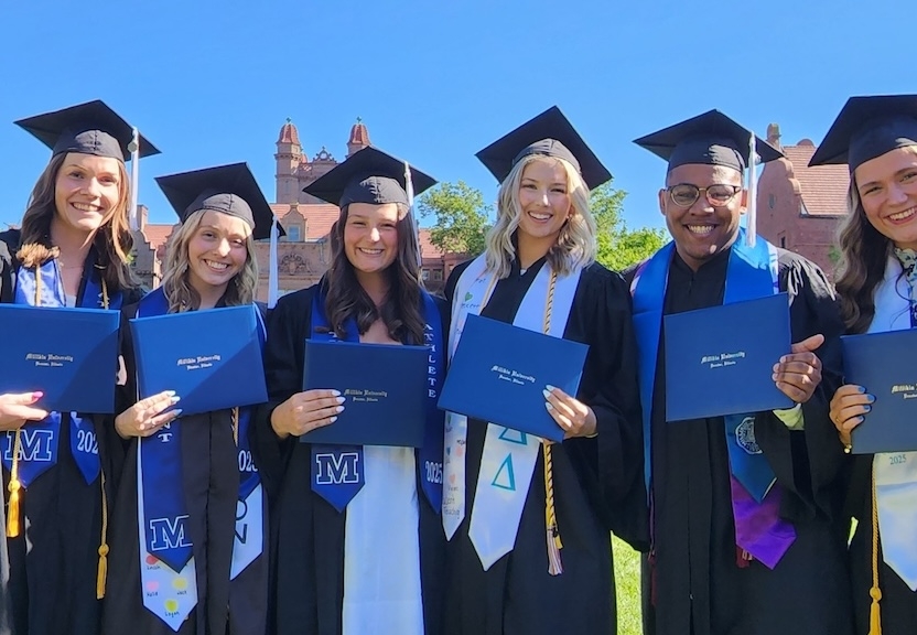 graduating students holding diplomas