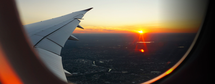 View looking out of airplane window at sunrise