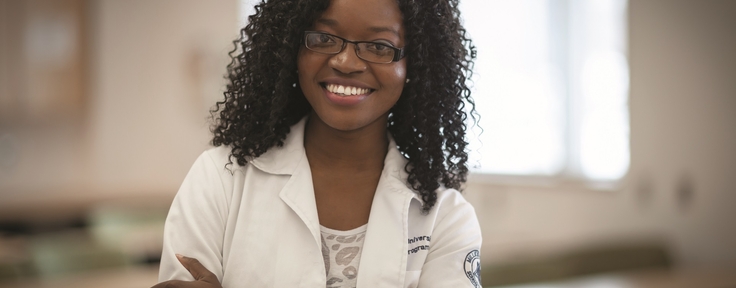 student in lab coat smiling