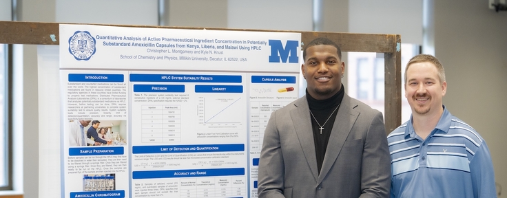 student and teacher standing in front of poster 