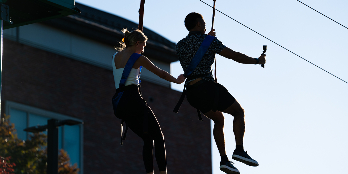 two students riding on a zipline
