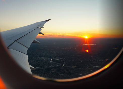 View looking out of airplane window at sunrise