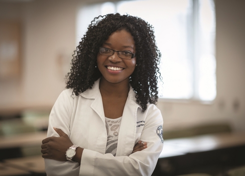 student in lab coat smiling