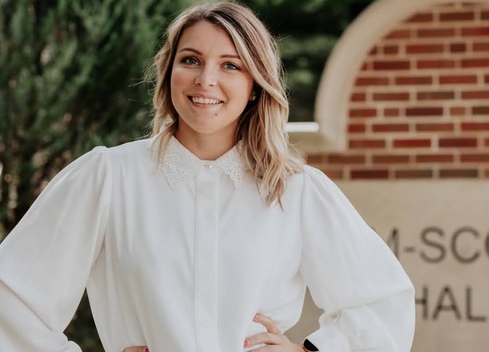 MBA Student standing in front of Adam-Scovill Hall 