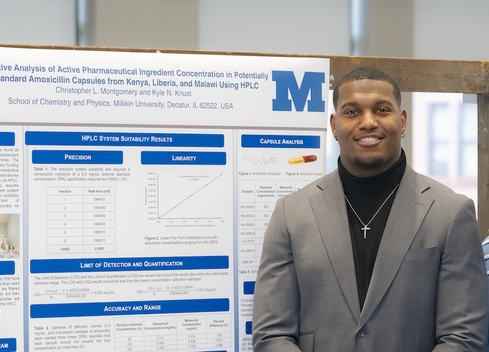 student and teacher standing in front of poster 