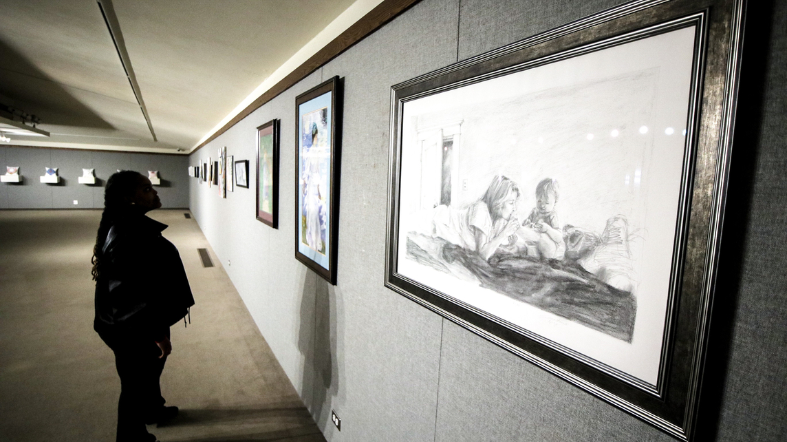 A student looks at work by School of Art &amp; Creative Media faculty. 