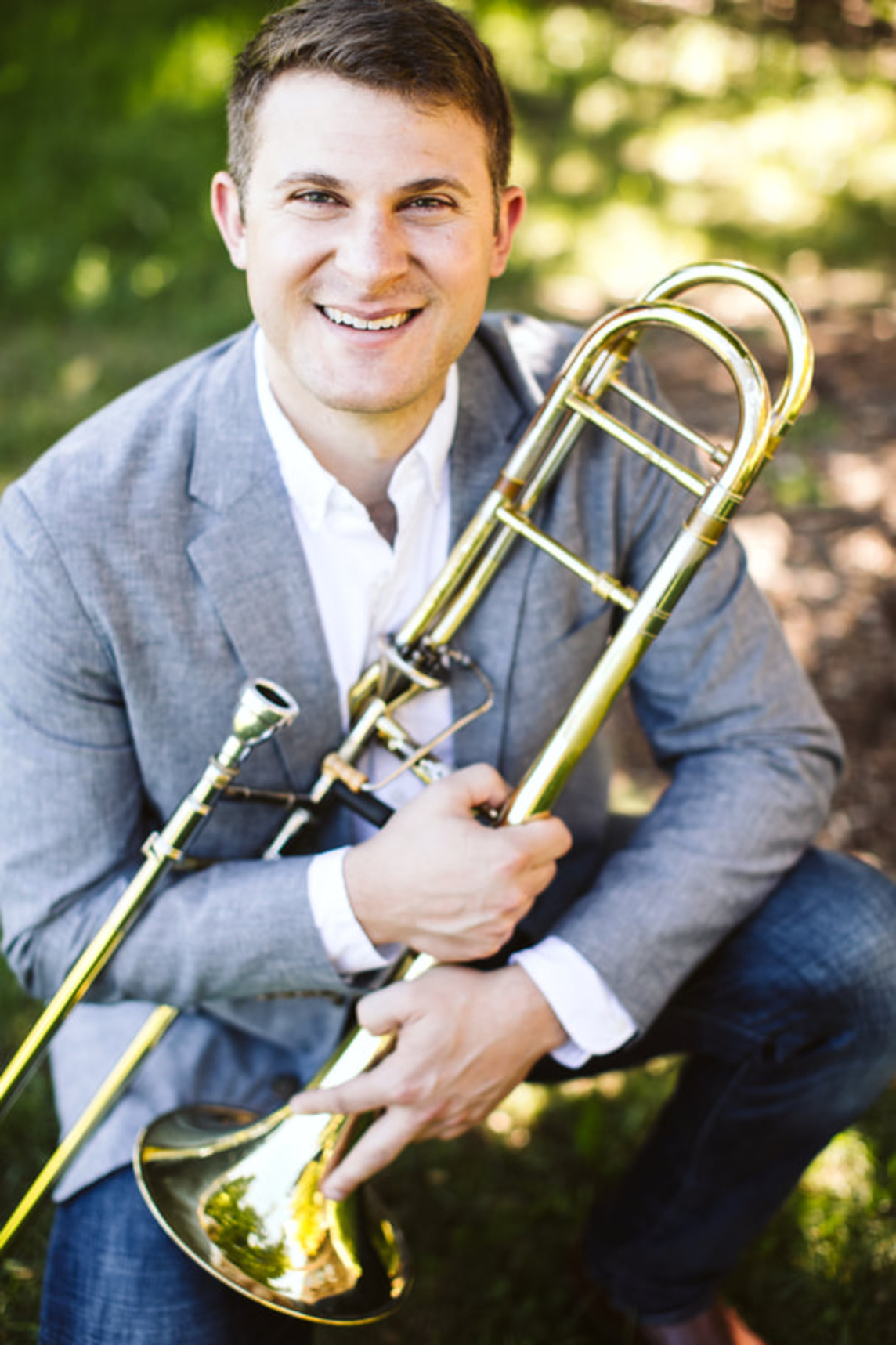 Headshot of featured musician Corey Sansolo, posing with his trombone.