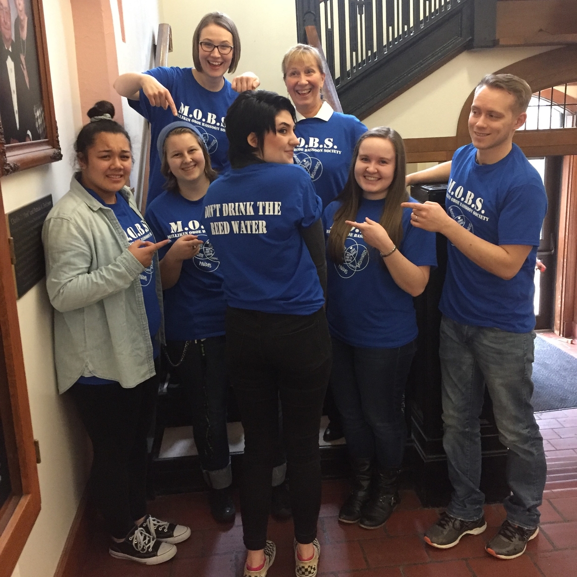 group of people on stairs pointing at shirt