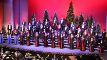 Millikin Choirs sing on Kirkland&#039;s stage for VESPERS. The stage has a red background and is decorated with Christmas trees. 