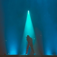 A man stands in the spotlight on stage. 